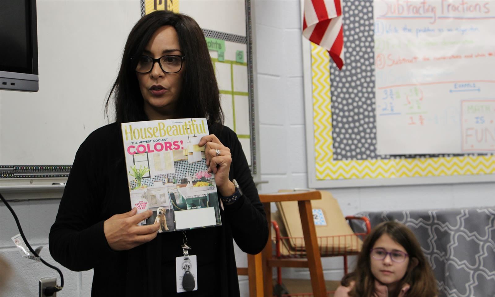 Teacher talks to students while holding magazine